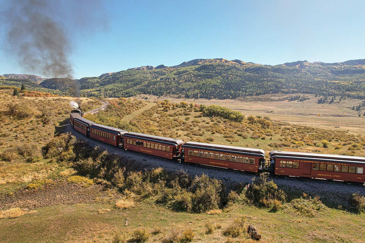 Cumbres & Toltec steam train gliding down the railway on a bright sunny day.