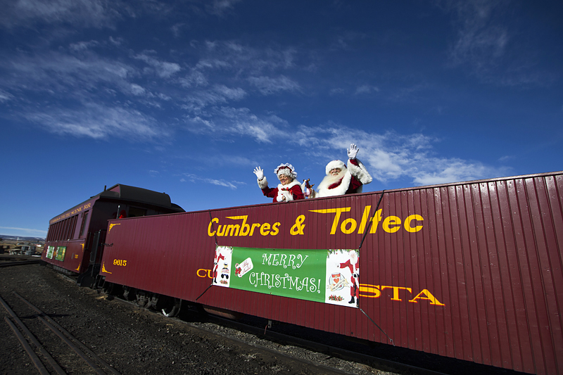 Santa and Mrs. Claus standing on Cumbres & Toltec railcar waiving to onlookers.